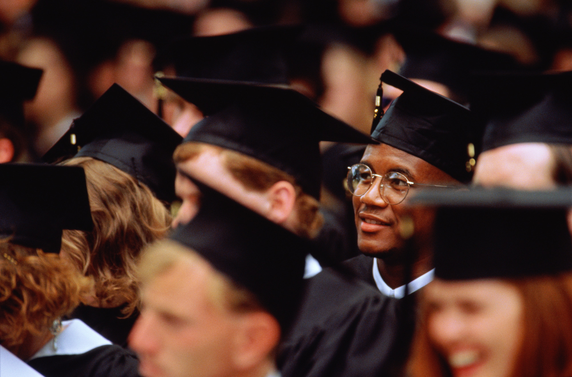 A group of graduating students in black caps and gowns sat down