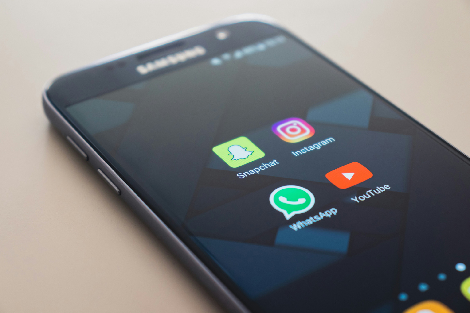 A smart phone with Snapchat, Instagam, WhatsApp, YouTube icons displayed
