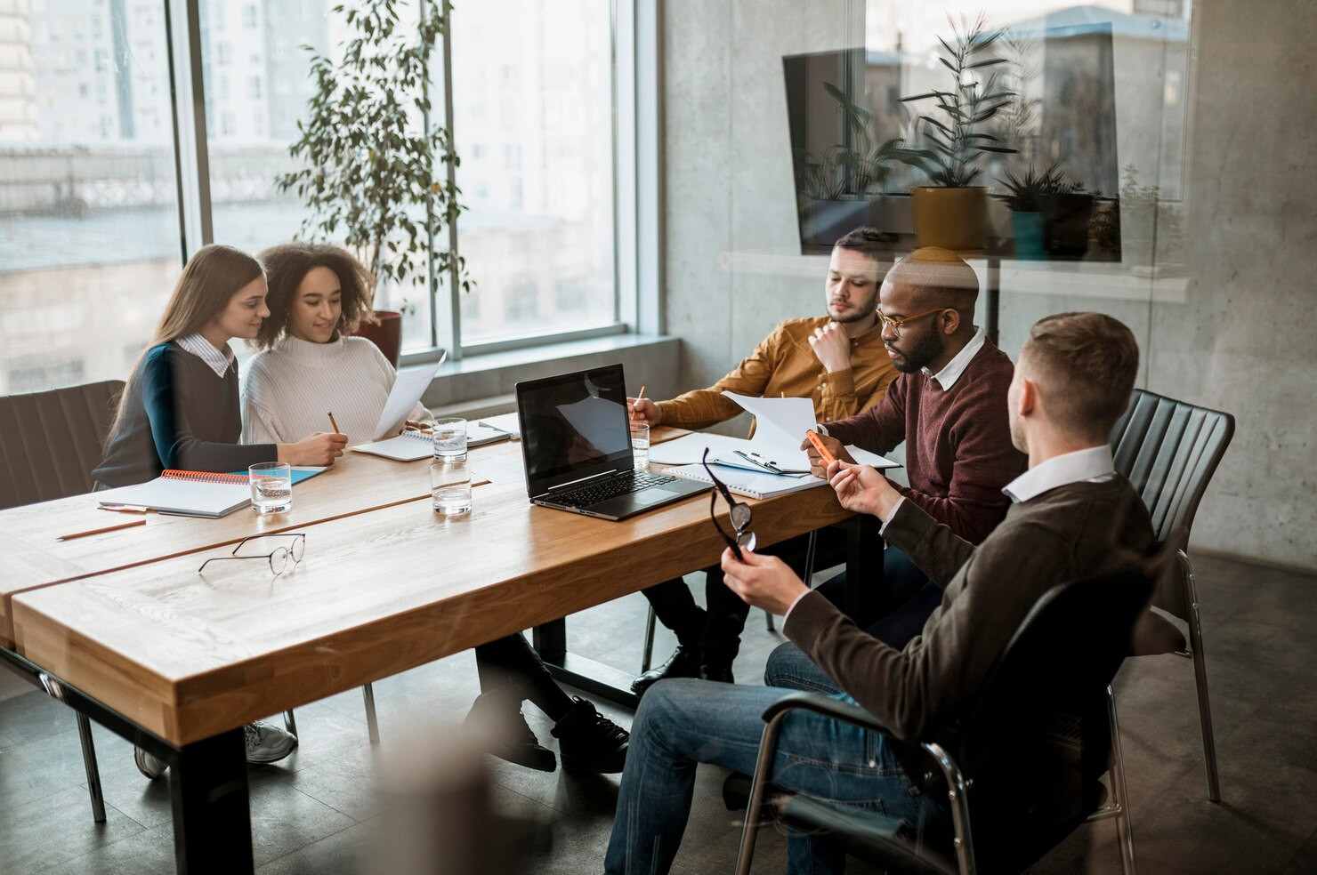 a group of colleagues gather in a modern, well-lit office to have a meeting