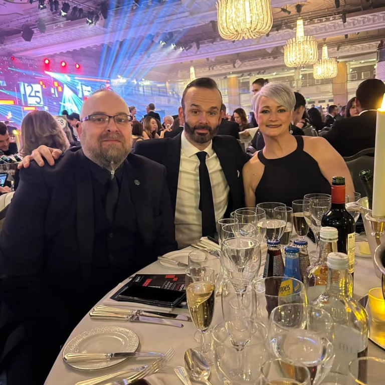 GLP Training Ranked 5th Best Place to Work in the UK - this is 3 members of the team in formal wear posing at their table at the ceremony event.