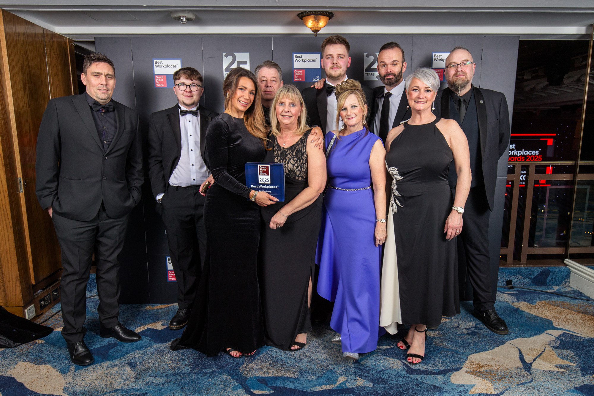 10 members of the GLP Training team in formal wear posing with the award at the ceremony event.