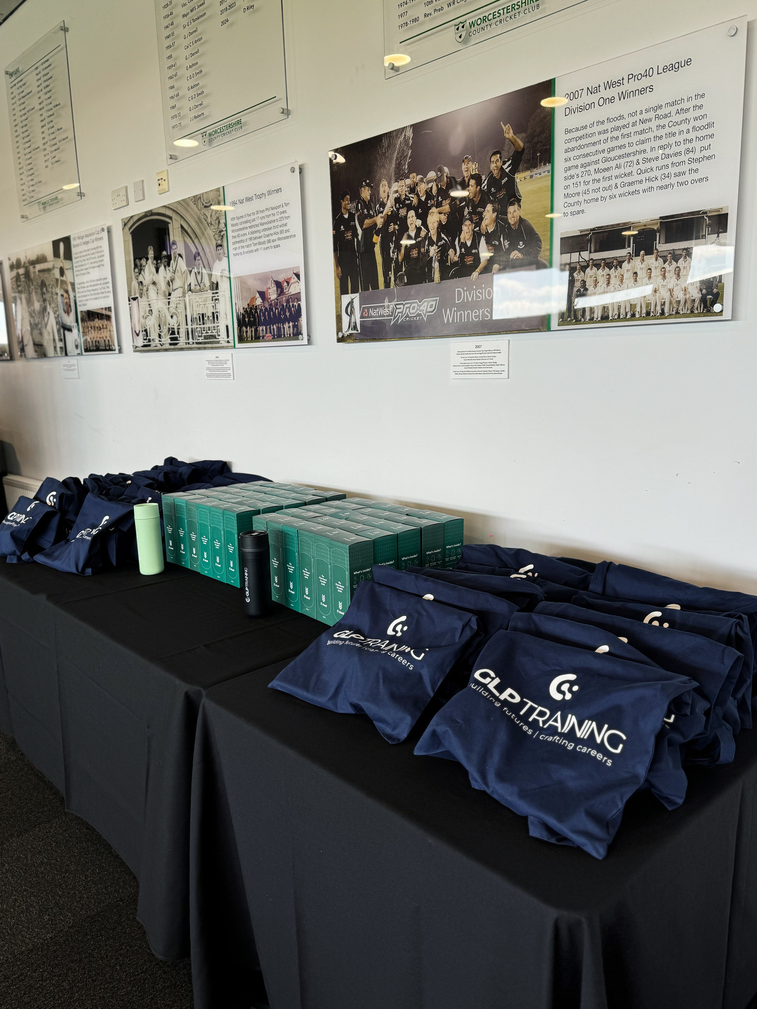 A GLP Training promotional table full of tote bags and branded items