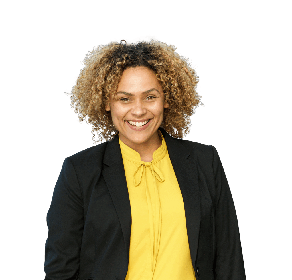 A middle-aged, black female with afro blonde hair smiles widely at the camera. She wears a black suit jacket over a bright yellow top.