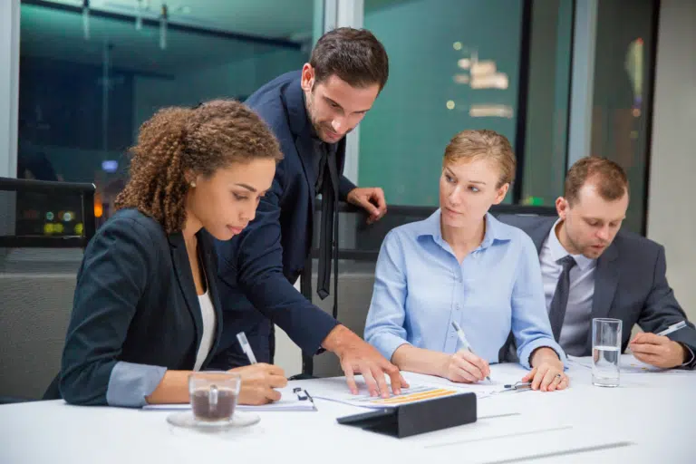 4 members of a leadership team work in a corporate office together in business wear.