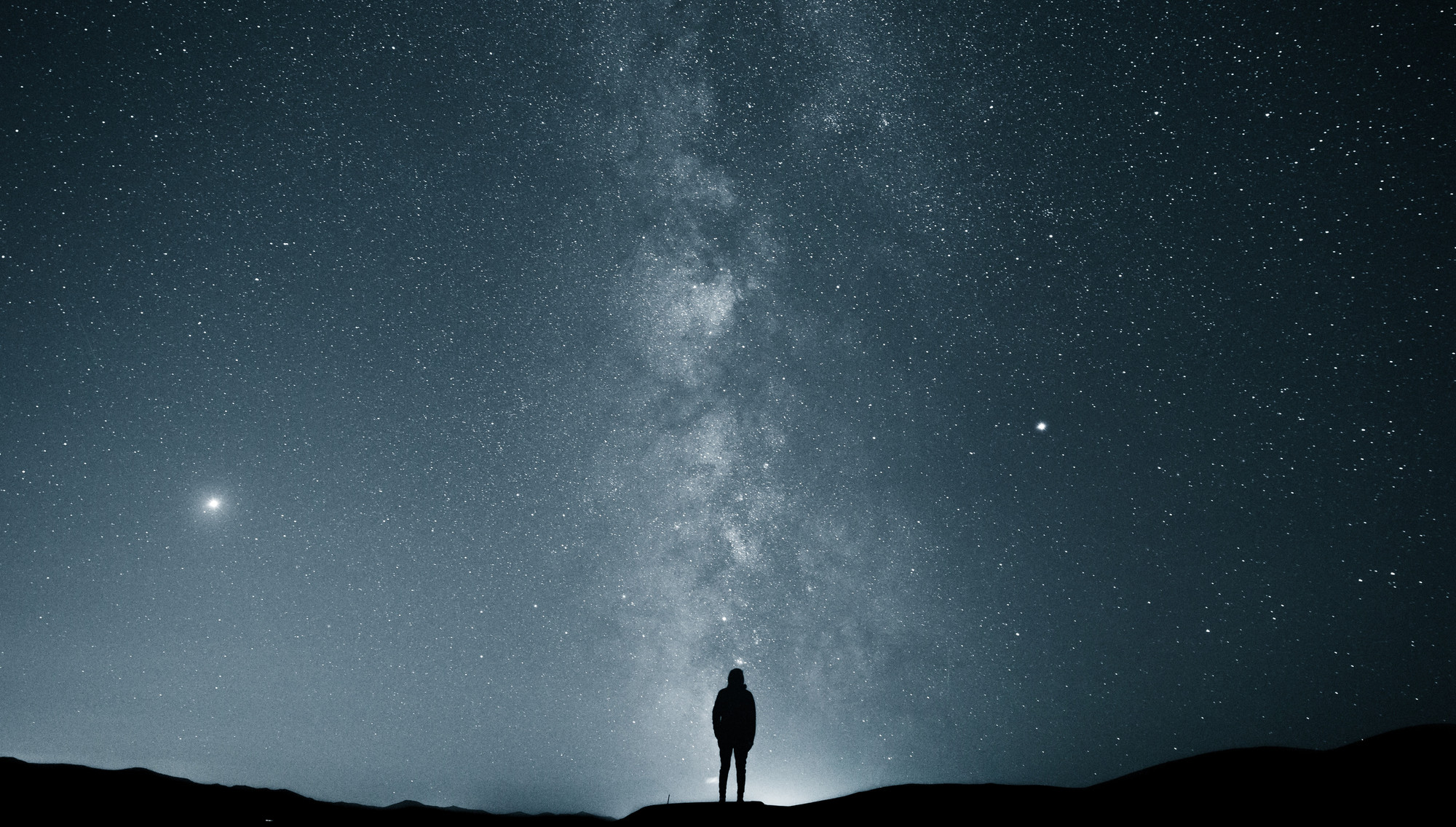 A figure looks up at a clear starry sky at night.