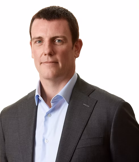 Gareth Sharpe smiles softly at the camera and wears a grey suit.