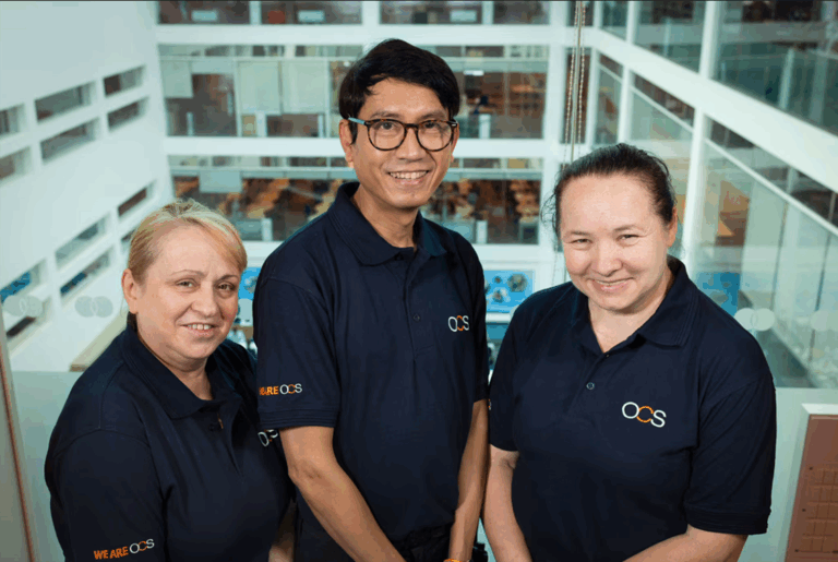 Three OCS employees smile directly at the camera in branded polo shirts