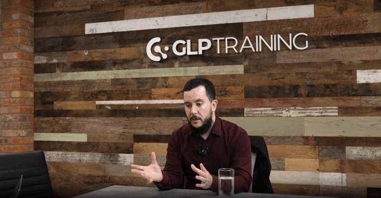 Peter Hutchinson - a man with dark hair and facial hair - sits in maroon shirt under a GLP Training logo talking at a table.