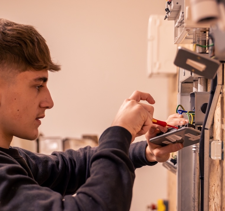A learner screwing an outlet on an electrical wall