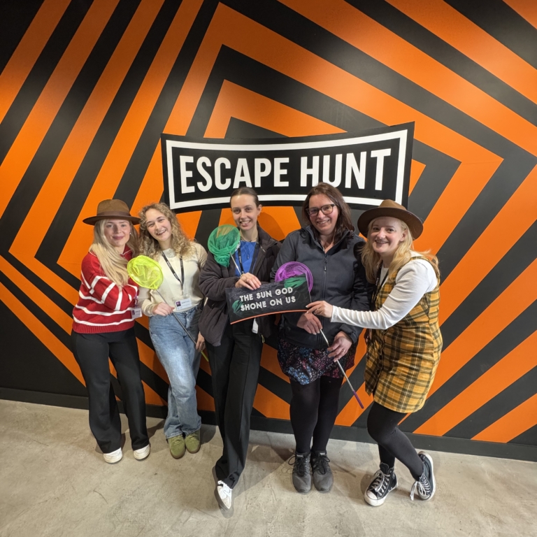 5 Women from GLP Training standing together for a group photo in front of the Escape Hunt Sign.
