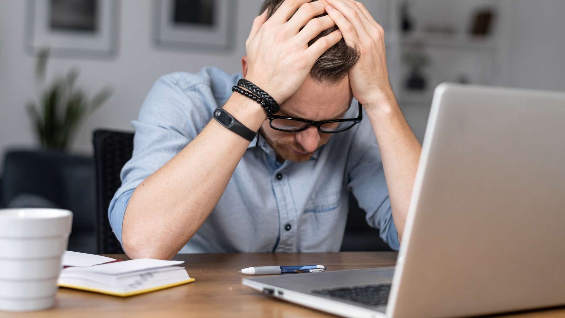 Man with head in hands sat at computer